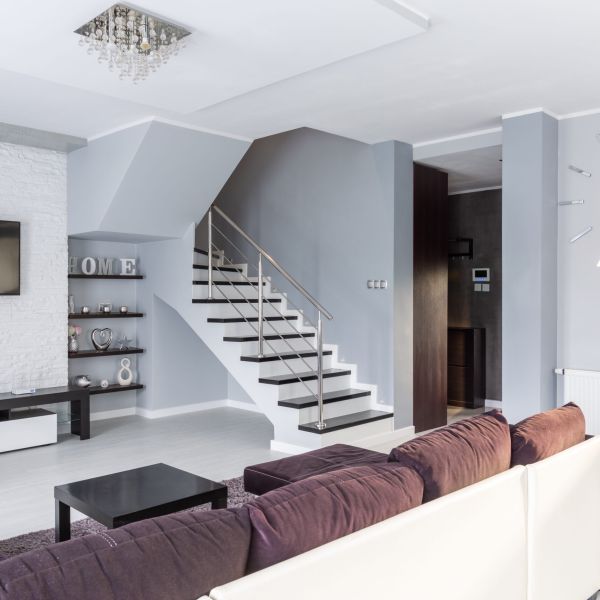 Fotografia wnętrz, fotografia wnętrz, zdjęcie ukazuje widok salonu ze schodami na piętro oraz kanapę